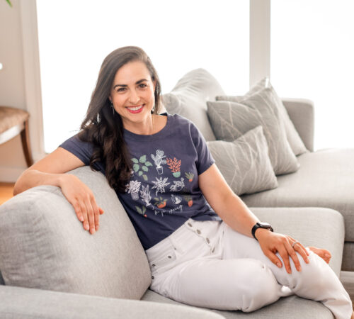 brown hair girl sitting on the coach smiling with white pants